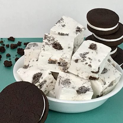 A bowl of cookies and cream marshmallows on green paper with chocolate sandwich cookies and cookie crumbles