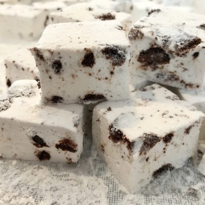 A stack of cookies and cream marshmallows on a white board with powdered sugar