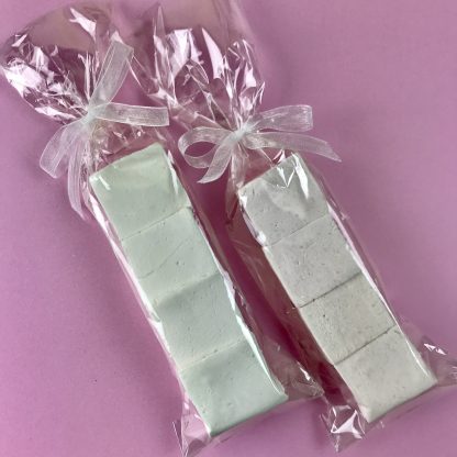 Two clear bags each containing four marshmallows and tied with organza ribbon. They are setting on a pink background.