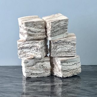 Two stacks each with three chocolate swirl marshmallows. They are setting on a dark marble board with a grey background.