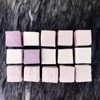 Strawberry, vanilla, and blueberry marshmallows arranged to look like the United States flag on a black marble board.