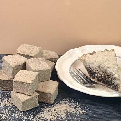A piece of shoofly pie and a fork are on a small plate, which is setting on a dark marble board. A pile of shoofly pie marshmallows is also on the board next to the plate. Crumbs are scattered about.