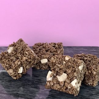Four chocolate crispies setting on a dark marble board. Two crispies are leaning against the others. The background is pink.