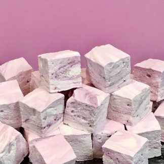A pile of peppermint marshmallows on a dark marble board with a pink background.