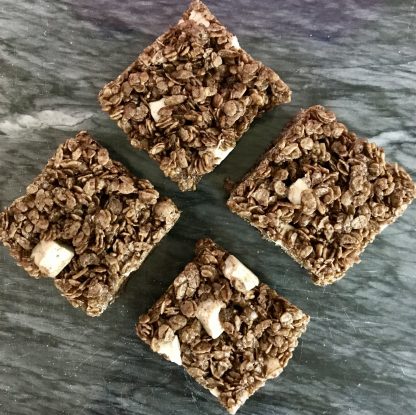 An overhead photo of four chocolate crispies setting on a dark marble board.
