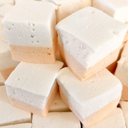 A pile of creamsicle marshmallows. The mallows have an orange layer on the bottom and a white layer on top.