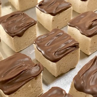 A closeup photo of peanut butter marshmallows topped with Belgian milk chocolate sitting on a sheet pan.