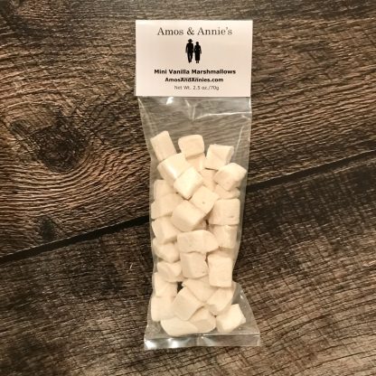 A package of mini vanilla marshmallows sets on a dark brown wood board.