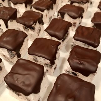Choco-Mint cookie marshmallows are lined up on a baking sheet. They contain gluten-free cookie pieces and are topped with Belgian dark chocolate.