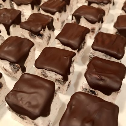 ChocoMint cookie marshmallows are lined up on a baking sheet. They contain gluten-free cookie pieces and are topped with Belgian dark chocolate.