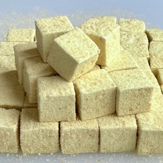 A stack of banana pudding marshmallows on a white board. The marshmallows are yellow and are coated with gluten-free cookie crumbs.