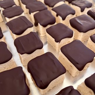 A closeup photo of peanut butter marshmallows topped with Belgian dark chocolate sitting on a sheet pan.