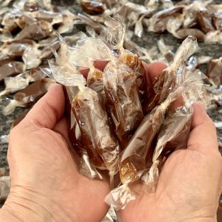 Two hands hold wrapped caramels