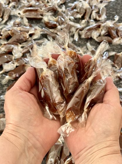 Two hands hold wrapped caramels