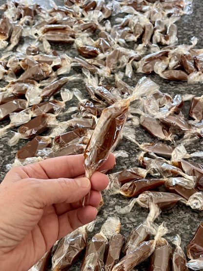 A hand holds a wrapped caramel